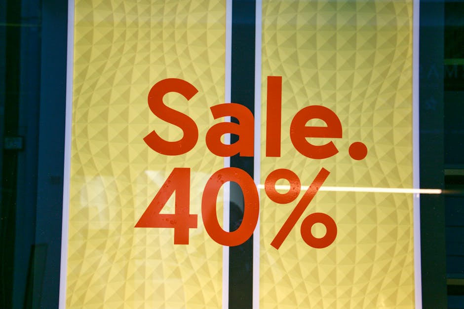 A close-up of a store window displaying a large yellow and beige patterned background with a prominent red text sign reading 'Sale. 40%'. The window appears to be part of a retail shop, with reflectio